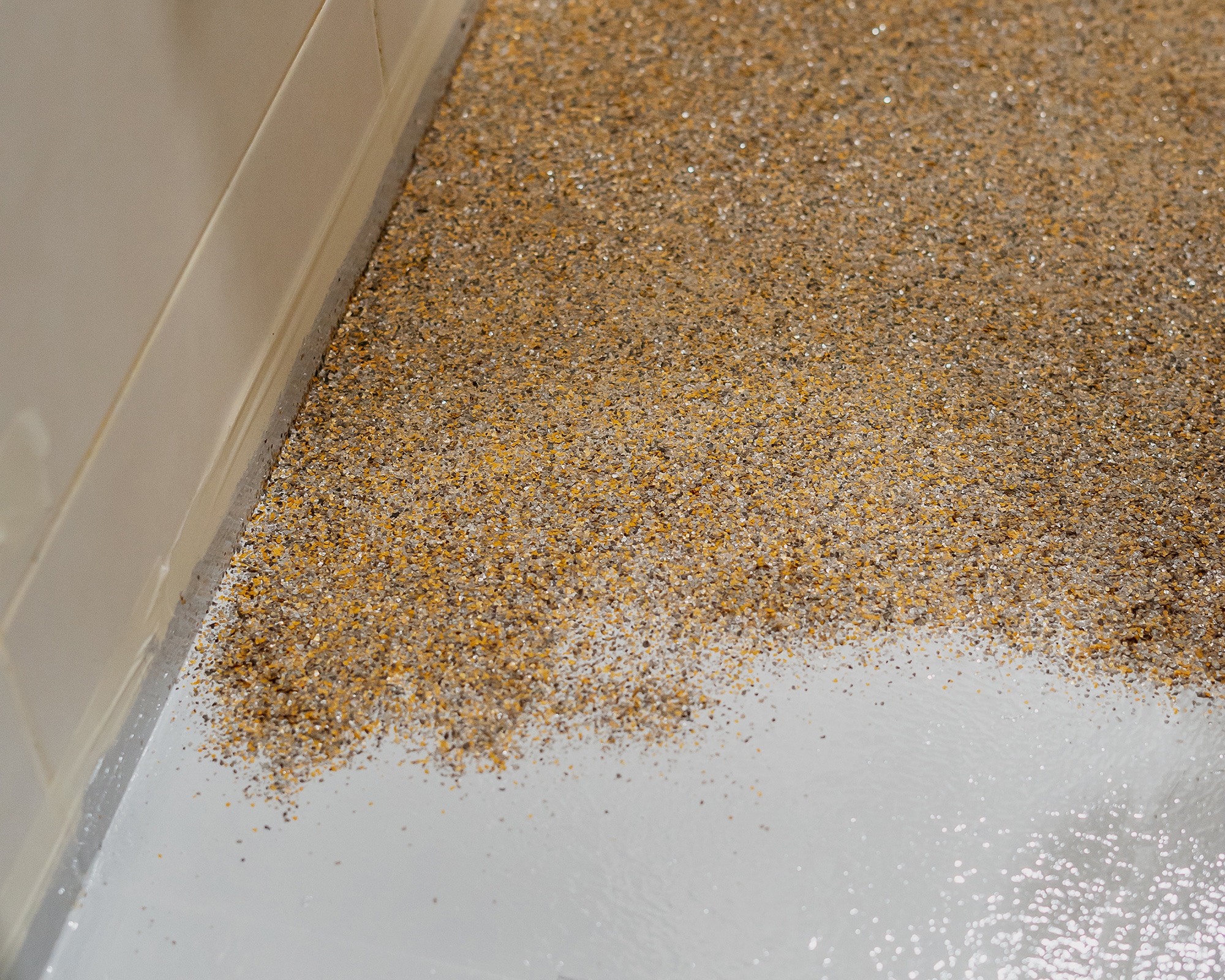 Quartz sand being broadcast into an epoxy base coat